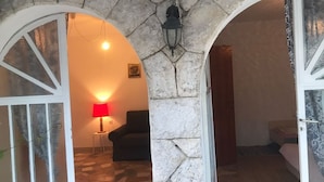 Et rum med en hvælvet stengang, en tændt lampe og en sofa.