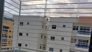 Vista desde un balcón con barandilla de metal, con vista a un edificio residencial de varios pisos y numerosas ventanas y balcones.