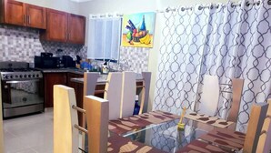 Una cocina moderna con armarios de madera, una estufa de acero inoxidable y una mesa de comedor de vidrio con individuales estampados.