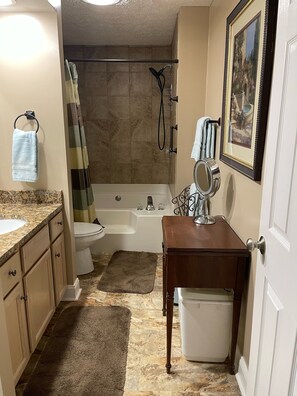 Une salle de bain équipée d’une baignoire, de toilettes, d’un lavabo et d’une petite table avec un miroir.