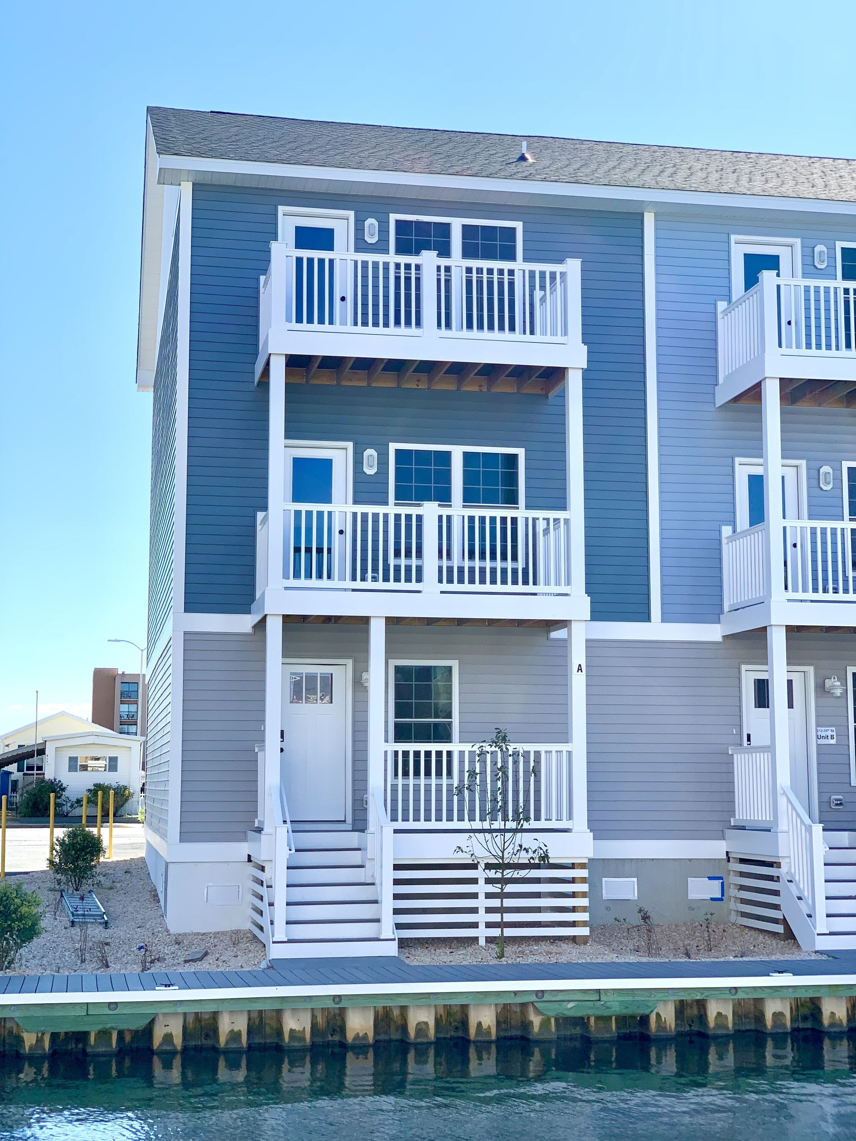 A multi-story building with balconies, a front door, and a small porch area.