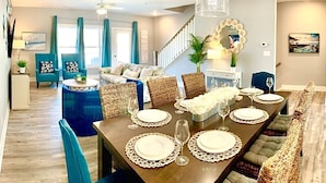 A dining area with a long table set for six, surrounded by wicker chairs and a bench. - IslandCoveParadise: Luxury-NewlyBuiltTH! OnTheWater-Boardwalk-Pool-w/2 CarGarage (Ocean City)