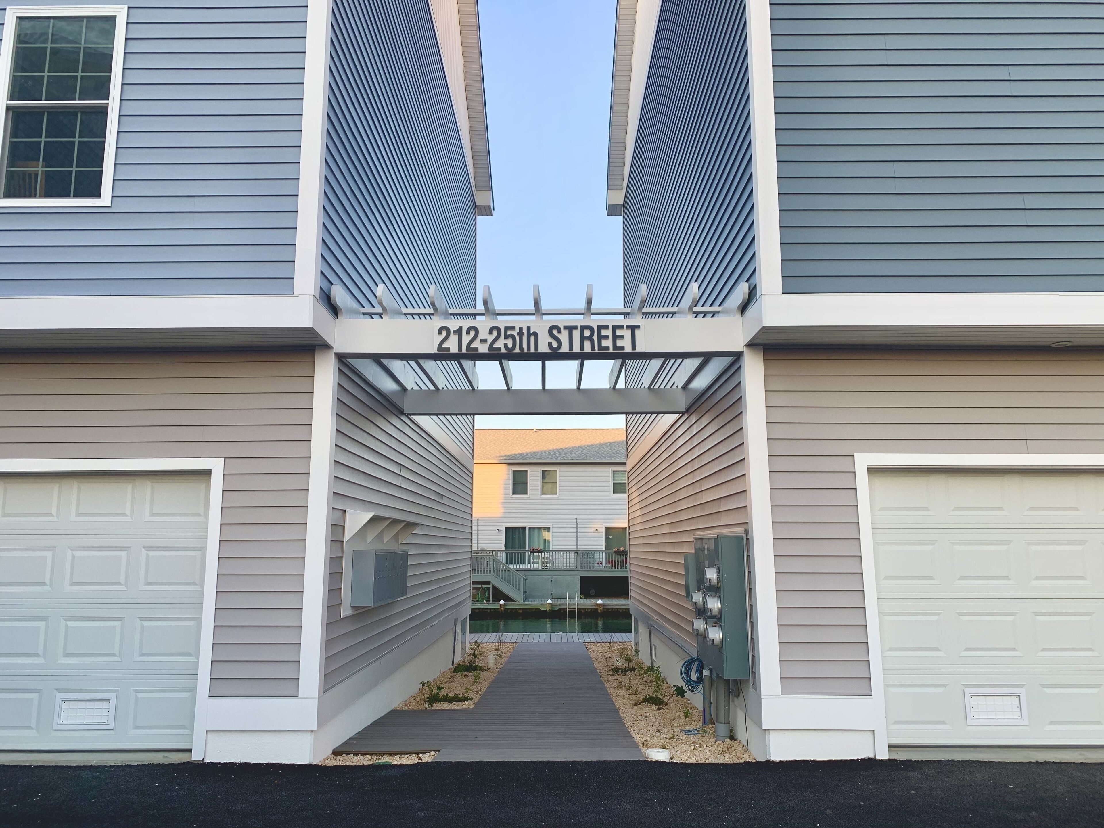 A residential building with a garage entrance, a nameplate reading '212-25th STREET,' and a pathway leading to a pool area.