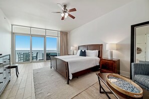 A hotel room with a large bed, a desk, a chair, a balcony with a view, and a ceiling fan. - Turquoise Place C1203 | Gorgeous, spacious, luxurious! Excellent reviews!! (Orange Beach)