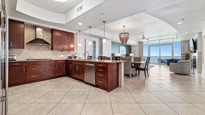 A modern kitchen with dark wood cabinets, a central island, and a dining area with a view.