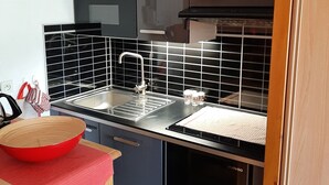 Eine moderne Küche mit schwarzen Schränken, einer Spüle aus Edelstahl und einer roten Schüssel auf der Arbeitsplatte.