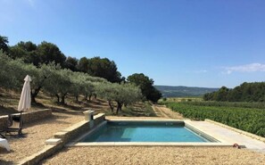 Piscina rectangular con borde de piedra, rodeada por una zona de grava.