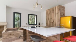 A modern kitchen with a white island, wooden accents, and a yellow refrigerator.