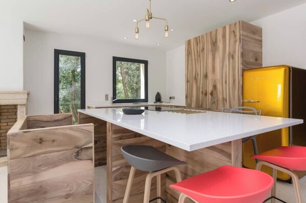 Una cocina moderna con una isla blanca, detalles de madera y un refrigerador amarillo.