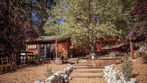 A rustic cabin with a wooden exterior, a front porch, and a sign that reads "PLAY ROOM".