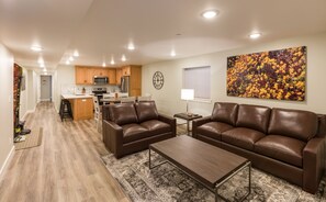 Ein modernes Wohnzimmer mit einem braunen Ledersofa, einem Holztisch und einem gemusterten Teppich.