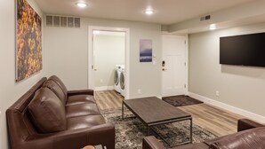 A modern living room with a brown leather couch, a wooden coffee table, and a flat-screen TV mounted on the wall. - Gorgeous brand new 2BR unit, sleeps 6.  Amazing ski location! (Salt Lake City)