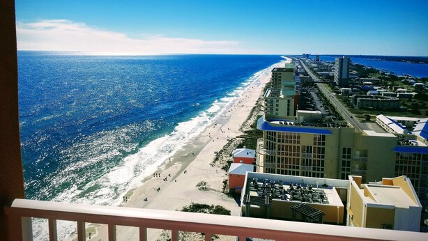 A coastal cityscape with a beach, buildings, and a clear sky.