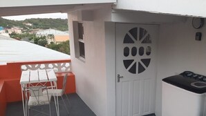 Eine kleine Küche mit einer weißen Tür, einem Fenster und einem Tisch mit Stühlen.