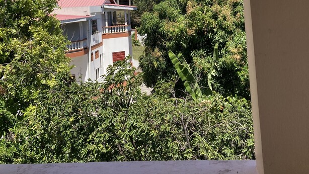 Blick vom Balkon auf eine Hügellandschaft mit Gebäuden, darunter ein weißes Gebäude mit rotem Dach und eine größere Struktur mit einer Kuppel.