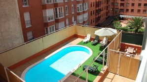 A rooftop pool with a clear blue pool, surrounded by lounge chairs and a sun umbrella. - Apartment (Madrid)