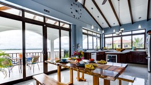 Une cuisine spacieuse dotée d’un grand îlot central, d’un coin repas avec une banquette et d’une vue sur l’océan.