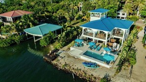 Une grande maison avec une piscine, plusieurs terrasses et un patio couvert.