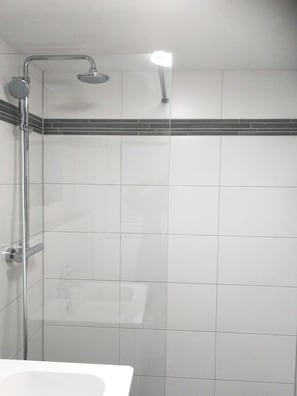 A shower with a handheld showerhead and a wall-mounted faucet.