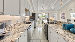 A modern kitchen with granite countertops, stainless steel appliances, and a central island. - Sandy Rocks | Ultimate Bundle: 2 Private Pet Friendly Homes, 2 Private Heated Pools, Walk to Beach! (Siesta Key)