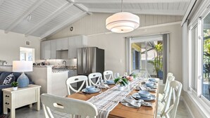 A modern kitchen with white cabinets, a stainless steel refrigerator, and a dining area with a wooden table set for six. - Sandy Rocks | Ultimate Bundle: 2 Private Pet Friendly Homes, 2 Private Heated Pools, Walk to Beach! (Siesta Key)