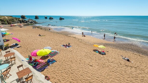 A beach with umbrellas, sun loungers, and a clear view of the ocean. - Magnificent South-facing Villa with Jaccuzzi, Beach and Corniche 200 m'away (Saint-Hilaire-de-Riez)