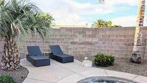 A spa area with a hot tub, two lounge chairs, a palm tree, and a brick wall. - CASA GRIS-Heated spool-Bring your fur baby! Enjoy Naranja Park and bike trails. (Tucson)