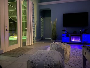 A modern living room with a flat-screen TV, a fireplace, and a potted plant.