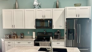 A kitchen with white cabinets, a black microwave, a stainless steel refrigerator, and a marble countertop. - Davenport Disney-Area Home ~ Private Pool & Hot Tub ~ Quiet Retreat (Davenport)