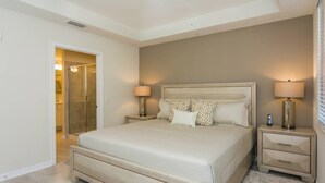A bedroom with a large bed, two bedside tables, and a walk-in closet.