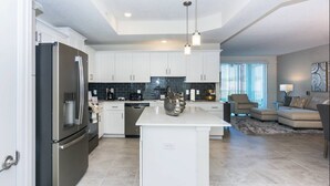 A modern kitchen with white cabinetry, a stainless steel refrigerator, and a central island.