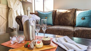 Una mesa con una botella de champán, dos copas y una variedad de postres sobre una tabla de madera.
