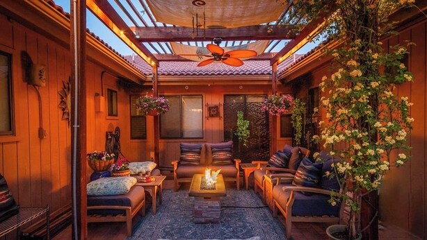 Un patio interior acogedor con paredes de madera, un ventilador de techo y una chimenea.