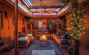 A cozy indoor patio with wooden walls, a ceiling fan, and a fire pit. - Whispering Creek B&B (Sedona)