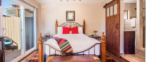 Un dormitorio con una cama grande, una silla de madera, un ventanal corredero y vistas al exterior.