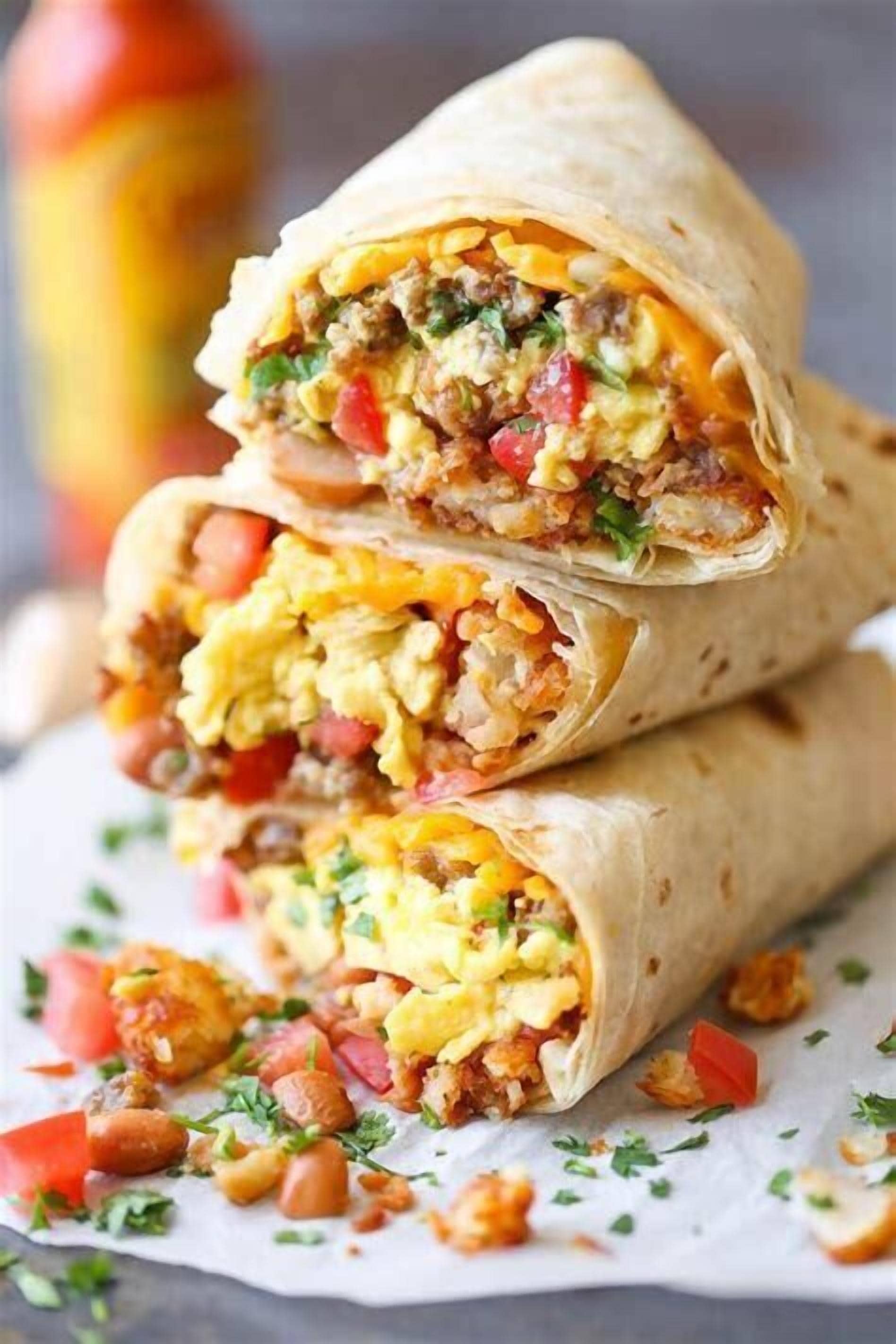 Un burrito cortado por la mitad, mostrando su relleno de huevos revueltos, carne y vegetales.