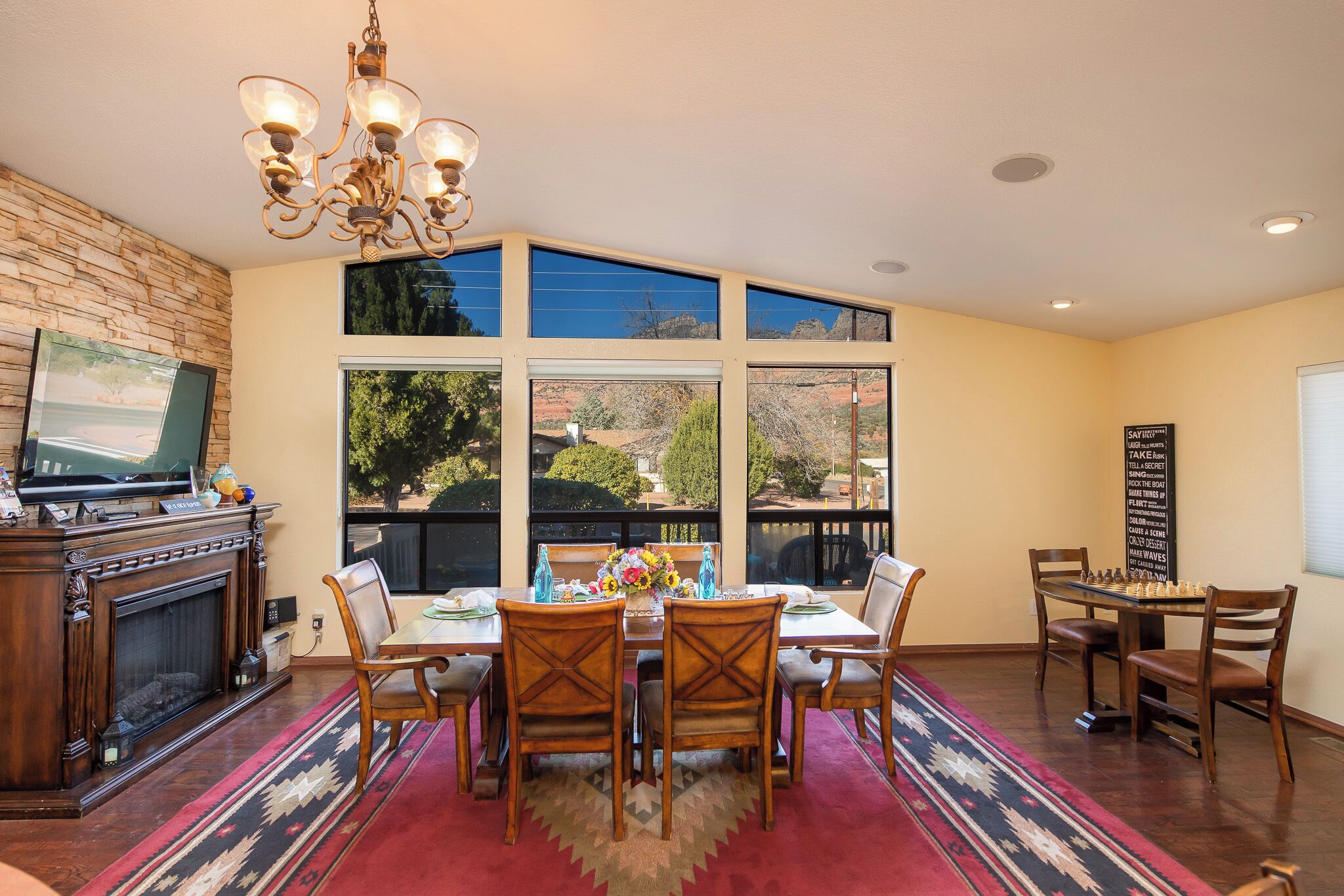 A dining area with a fireplace, large windows, and a chandelier.
