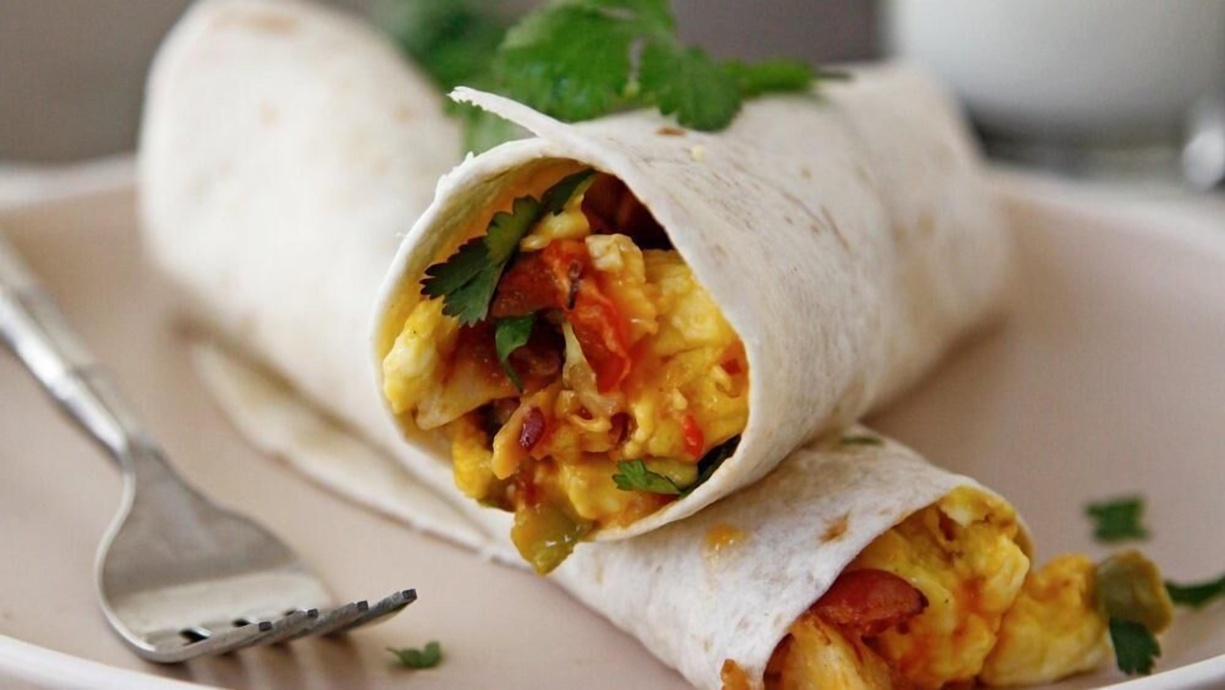 Un burrito en un plato con un tenedor a un lado.