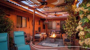 Relax by the fire pit in a sheltered outdoor seating area surrounded by comfortable seating and lush greenery.