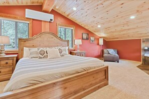 A bedroom with a wooden bed, two bedside tables, a nightstand, a chair, and a window.