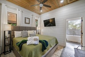 Ein Schlafzimmer mit einem Bett, einem Fernseher, einem Fenster und einem Badezimmer.