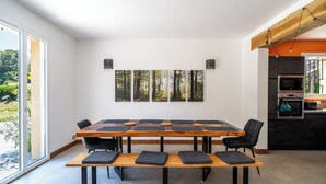 A modern kitchen with a large dining table and chairs, a wooden ceiling, and a view of the outdoors. - Charming country house in a wooded garden in Perigord Vert (La Coquille)