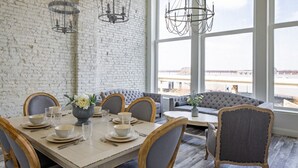 A dining area with a brick wall, large windows, and a view of the outside.