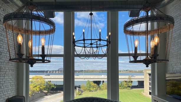A room with large windows, a chandelier, a sofa, and a table.