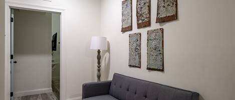 Una habitación con un sofá gris, una lámpara blanca y cuatro piezas de arte rústico en la pared.