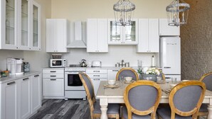 A kitchen with white cabinets, a microwave, an oven, and a dining table with chairs.