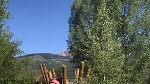 A playground with a red slide and climbing structures, surrounded by trees and a mountain in the background. - Newly Renovated, 3 bd, 3 bath on shuttle route (Vail)