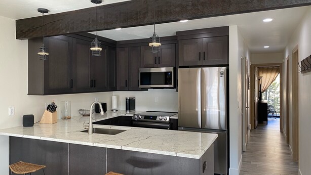 A modern kitchen with dark cabinets, stainless steel appliances, and a marble countertop. - Newly Renovated, 3 bd, 3 bath on shuttle route (Vail)