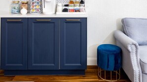A kitchen with dark blue cabinets, a white countertop, and a blue stool. - Gold Suite by Hollyhock. Executive-Level Living (Louisville)