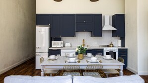 A modern kitchen with dark cabinets, white appliances, and gold accents. - Gold Suite by Hollyhock. Executive-Level Living (Louisville)